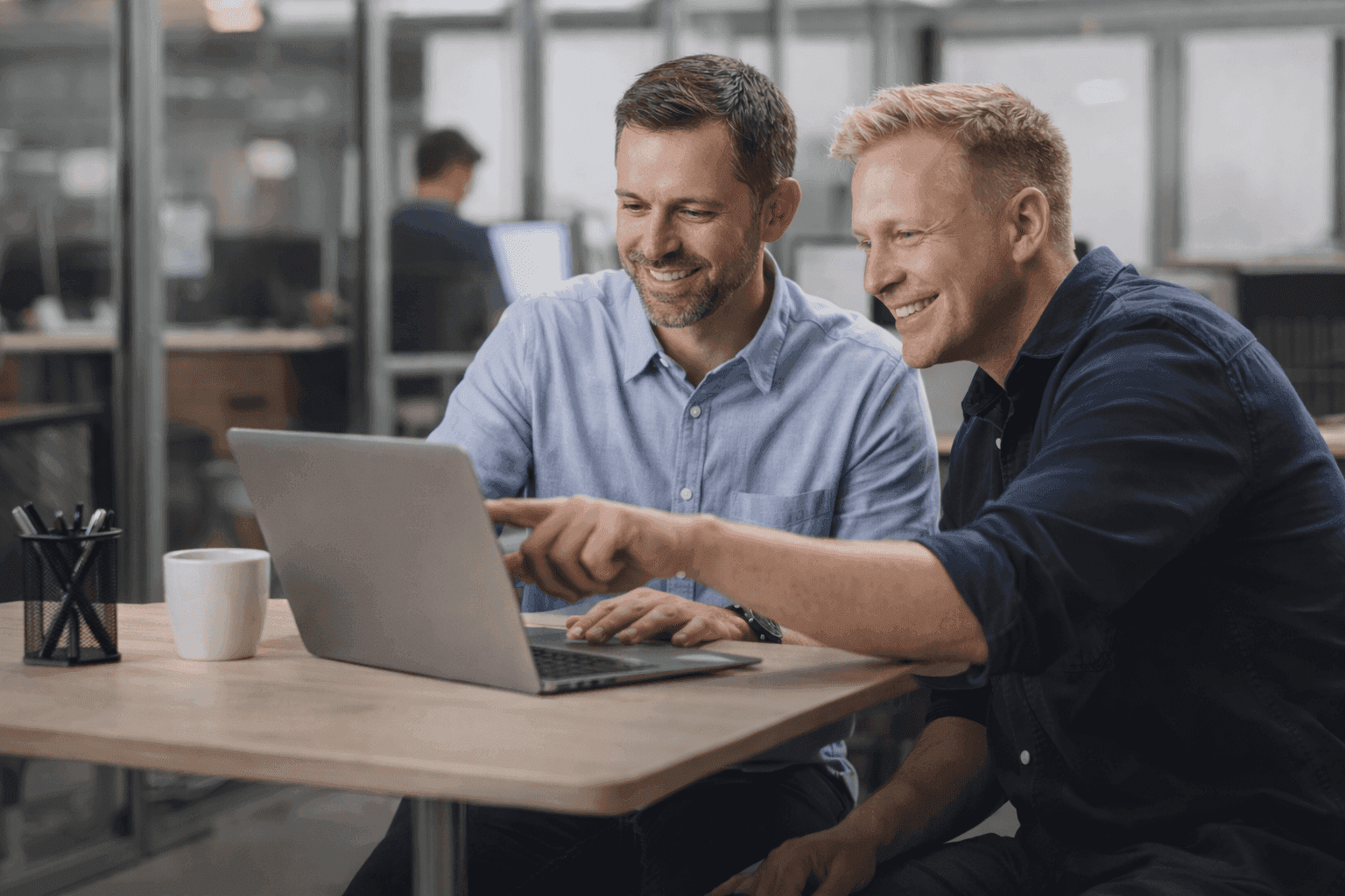 Twee Joinly-collega's bekijken samen een laptop aan een werktafel