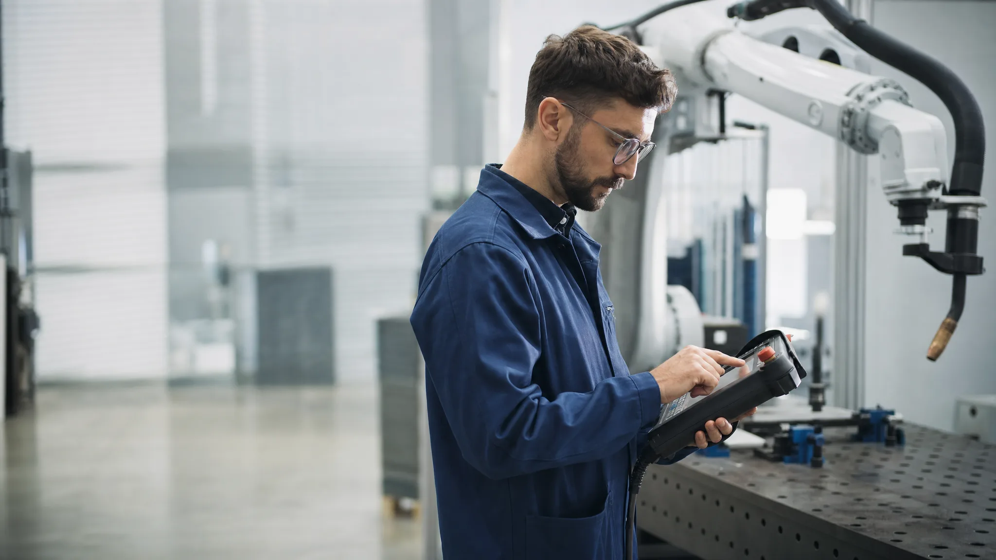 An engineer programming a welding robot in a production hall