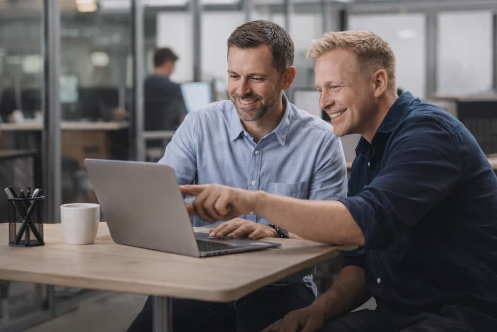 Twee collega's overleggen achter een laptop